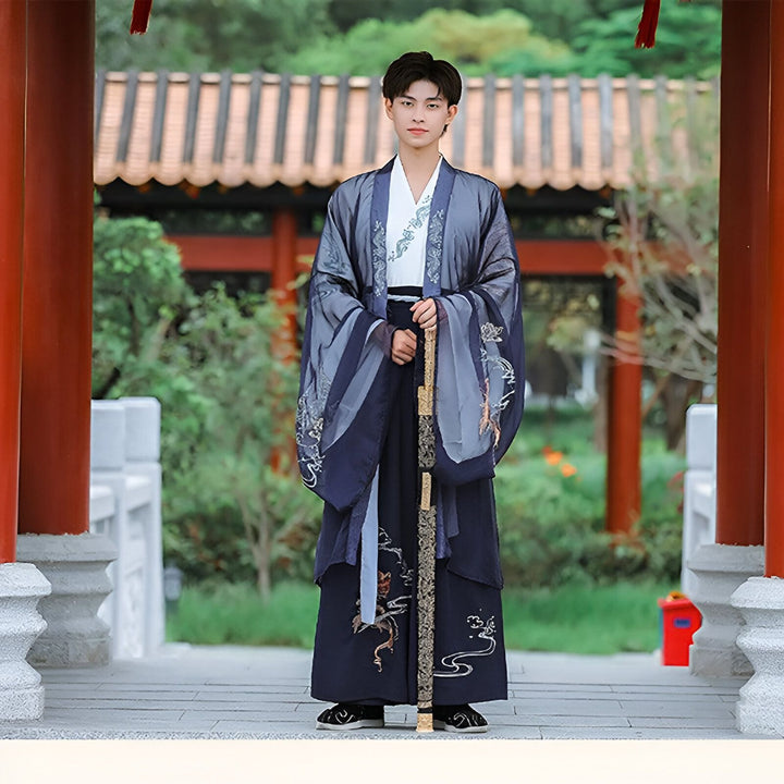 Homme portant un kimono traditionnel bleu et gris avec des motifs brodés. Kimono élégant pour occasions spéciales. Découvrez notre collection de kimonos uniques.