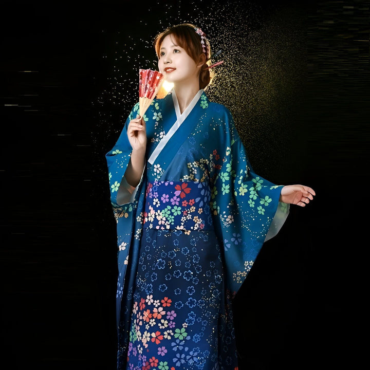 Jeune femme en kimono bleu à motifs floraux, tenant un éventail rouge. Mode japonaise traditionnelle, vente de kimonos en ligne.