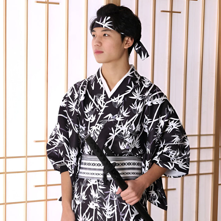 Homme en kimono noir et blanc avec motif de bambou, portant un bandeau assorti et tenant un katana. Découvrez notre collection de kimonos japonais traditionnels et modernes.