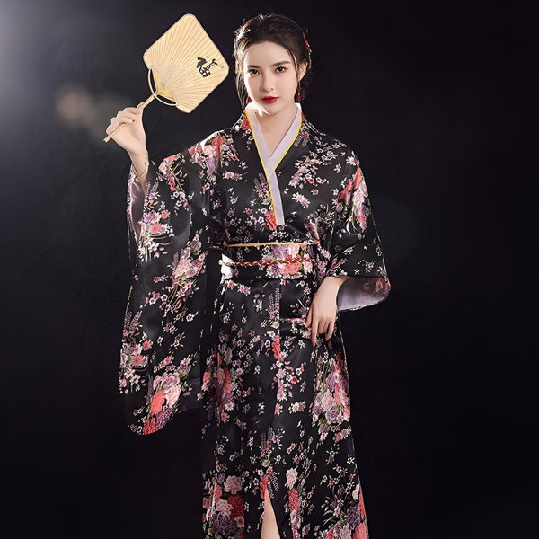Femme portant un kimono noir à motifs floraux, tenant un éventail. Kimonos traditionnels et modernes à vendre.