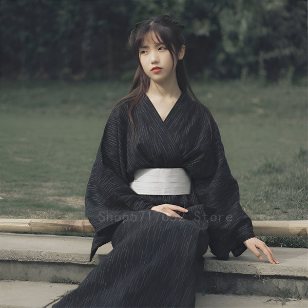 Jeune femme portant un kimono noir avec des rayures blanches. Élégance japonaise. Découvrez notre collection de kimonos uniques.