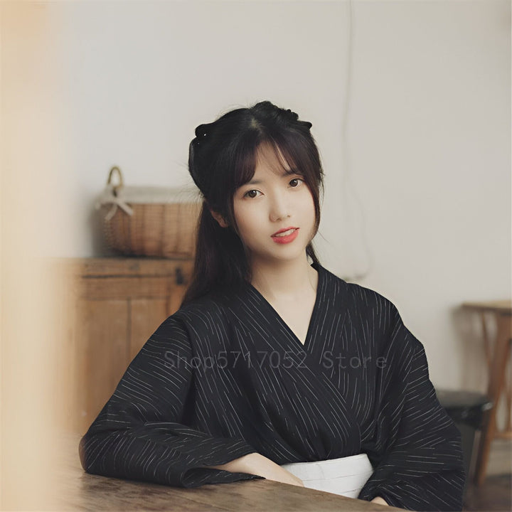 Jeune femme asiatique portant un kimono traditionnel noir à rayures. Vente de kimonos authentiques. Découvrez notre collection unique de kimonos.
