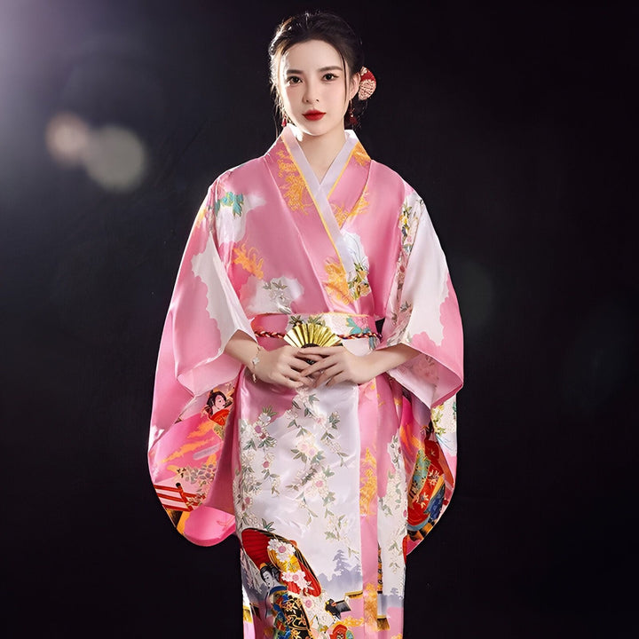 Femme portant un kimono rose à motifs floraux et éventail doré. Vente de kimonos traditionnels japonais en ligne.