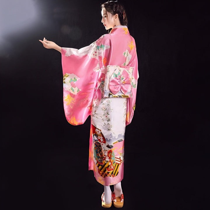 Femme portant un kimono rose traditionnel avec des motifs floraux et une ceinture obi décorée. Kimonos disponibles à l'achat.