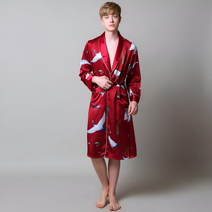 Homme portant un kimono en soie rouge avec des motifs de grues blanches. Peignoir japonais élégant et confortable, idéal pour la détente à la maison. Découvrez notre collection de kimonos pour hommes.