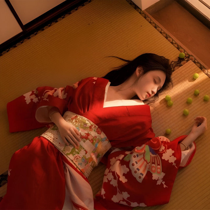 Femme asiatique portant un kimono rouge traditionnel, allongée sur un tatami. Kimonos de haute qualité disponibles à l'achat.