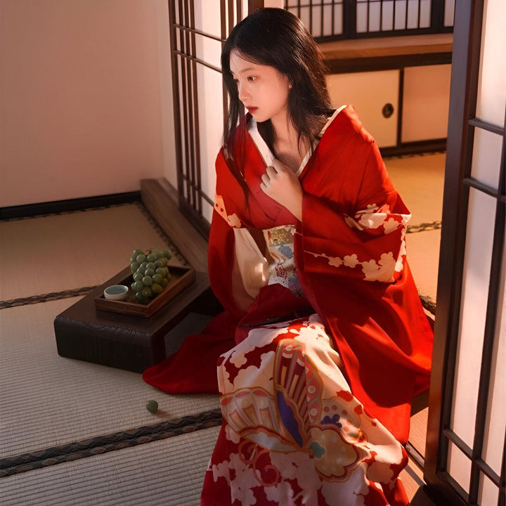 Femme en kimono rouge traditionnel assis sur un sol de tatami. Kimono fleuri, ambiance japonaise. Découvrez notre collection de kimonos authentiques.
