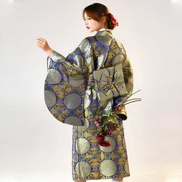 Femme portant un kimono bleu et or avec motifs floraux. Vue de dos, elle tient des fleurs. Découvrez notre collection de kimonos traditionnels et modernes.