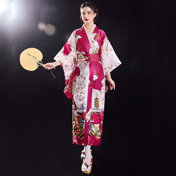 Femme en kimono traditionnel japonais rose et blanc avec motifs floraux et de pagode, tenant un éventail. Vente de kimonos authentiques.