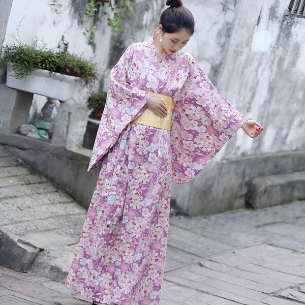 Femme portant un kimono fleuri violet, style japonais traditionnel. Découvrez notre collection de kimonos uniques.