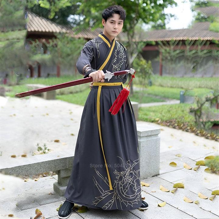 Homme en kimono traditionnel tenant un katana. Kimono noir avec détails dorés et ceinture jaune. Idéal pour cosplay, événements culturels. Vêtements japonais authentiques en vente.