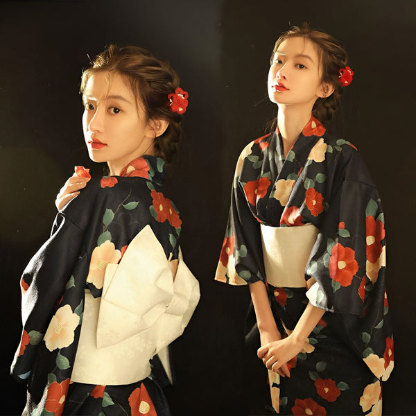 Femme portant un kimono noir à motifs floraux rouges et roses, obi blanc, coiffure ornée de fleurs rouges. Vêtements traditionnels japonais en vente.