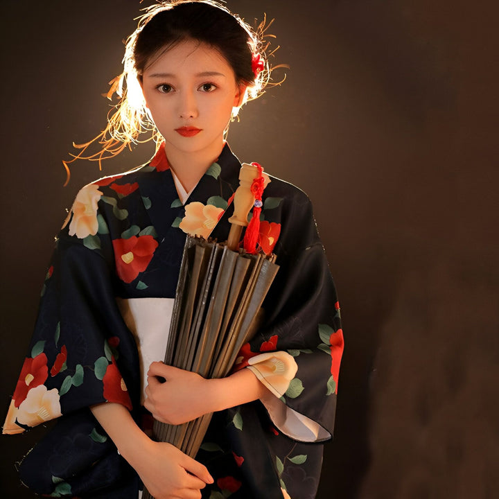 Jeune femme portant un kimono à motifs floraux rouges et beiges, tenant un parasol fermé. Kimonos japonais authentiques à vendre.