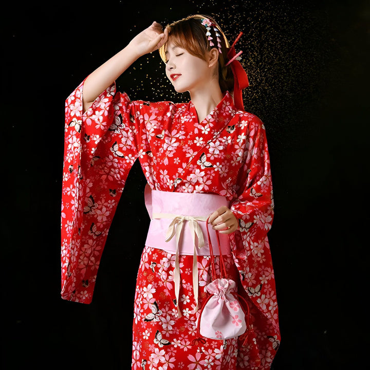 Jeune femme en kimono rouge à motifs de fleurs et papillons blancs, coiffée d'ornements traditionnels, tenant un petit sac rose. Costume japonais traditionnel.