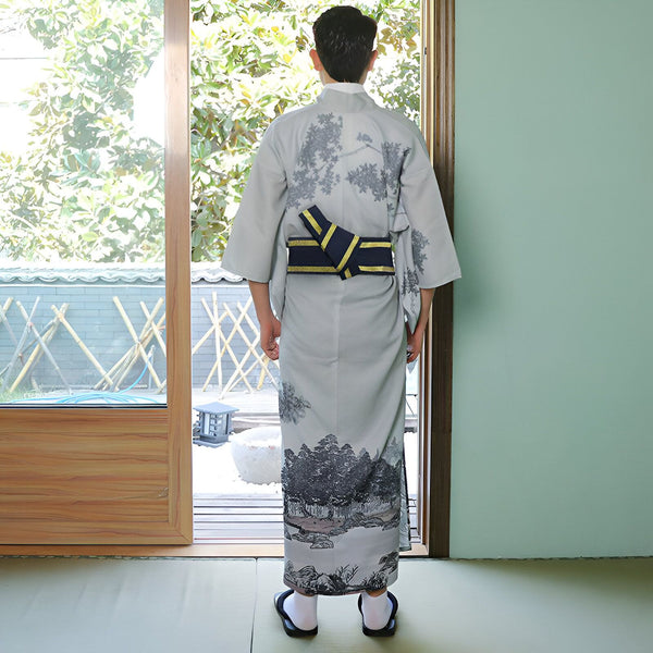 Homme portant un kimono gris avec des motifs d'arbres, ceinture obi noire et or. Vue de dos. Kimonos à vendre.