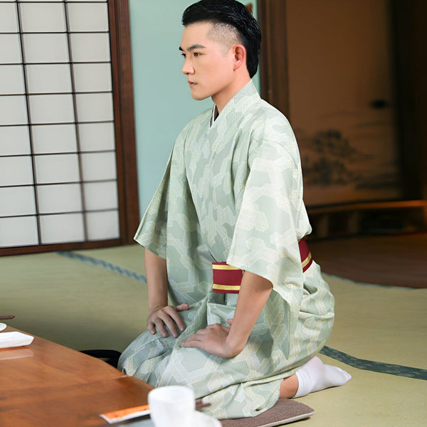 Homme agenouillé portant un kimono vert clair à motifs. Vente de kimonos traditionnels et modernes. Explorez notre collection unique de kimonos pour hommes.