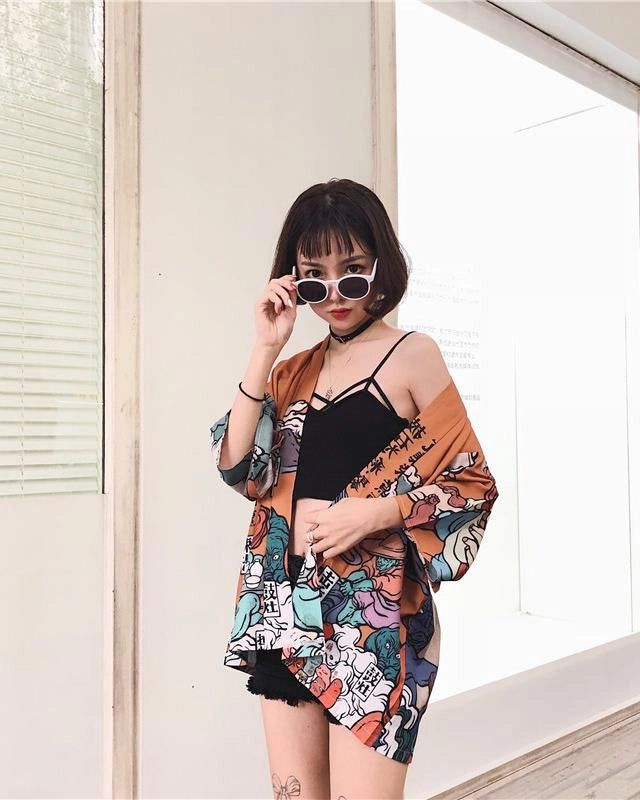 Femme portant un kimono orange imprimé, lunettes de soleil blanches, et haut noir. Vêtements japonais à la mode. Achetez des kimonos uniques sur notre boutique en ligne.