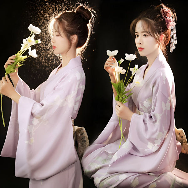 Deux femmes élégantes en kimonos lilas fleuris tiennent des fleurs blanches. Découvrez notre collection de kimonos uniques.