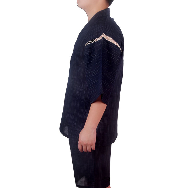 Homme portant un kimono japonais bleu marine avec un motif à rayures blanches. Détail dentelle beige sur l'épaule. Ensemble kimono et short, vêtement traditionnel revisité. Parfait pour un style japonais décontracté.