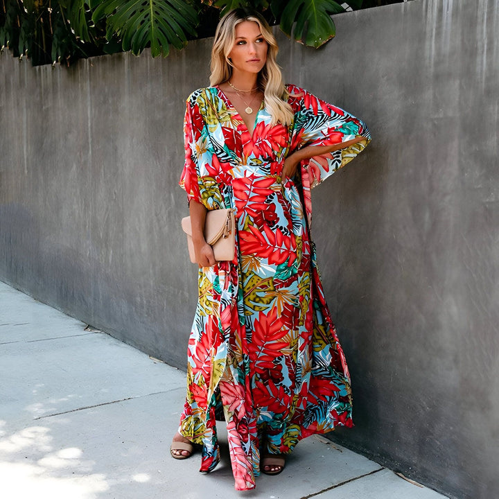 Femme blonde portant un kimono long à motifs floraux colorés. Vêtement de plage élégant et confortable, idéal pour l'été. Disponible dans notre boutique.