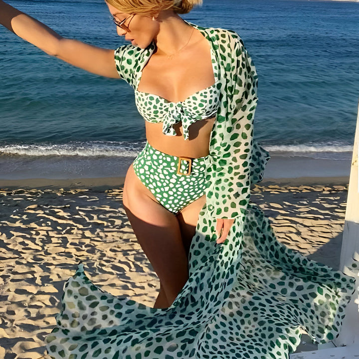 Femme à la plage portant un kimono vert à motifs et un maillot de bain assorti. Kimonos élégants pour la plage et l'été. Découvrez notre collection de kimonos en ligne.