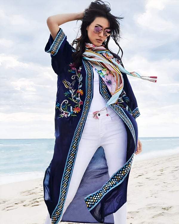 Femme portant un kimono bleu marine brodé sur la plage. Foulard coloré, lunettes de soleil roses. Mode kimono d'été, vêtements de plage élégants.