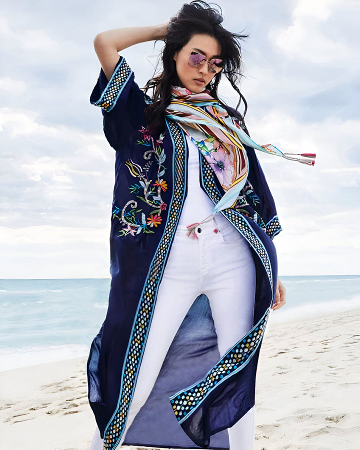 Femme portant un kimono bleu marine brodé sur la plage. Foulard coloré, lunettes de soleil roses. Mode kimono d'été, vêtements de plage élégants.