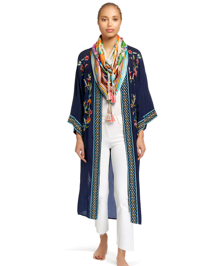 Femme portant un kimono bleu marine brodé de fleurs, avec un foulard coloré. Vêtement ample et élégant, idéal pour toutes occasions. Découvrez notre collection de kimonos uniques!