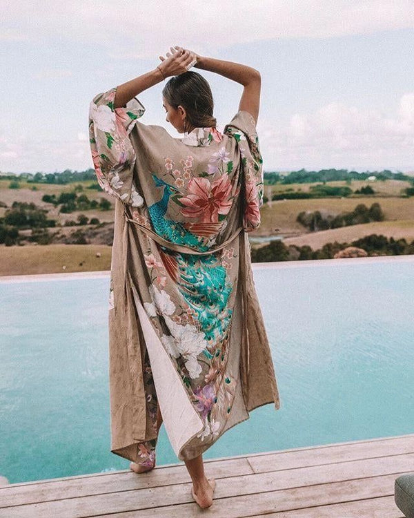 Femme de dos en kimono imprimé paon près d'une piscine. Kimonos élégants et confortables. Découvrez notre collection de kimonos en ligne.