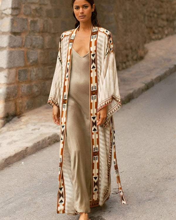 Femme portant un kimono beige à motifs géométriques. Notre collection de kimonos offre un style unique et élégant. Découvrez nos nouveaux modèles !