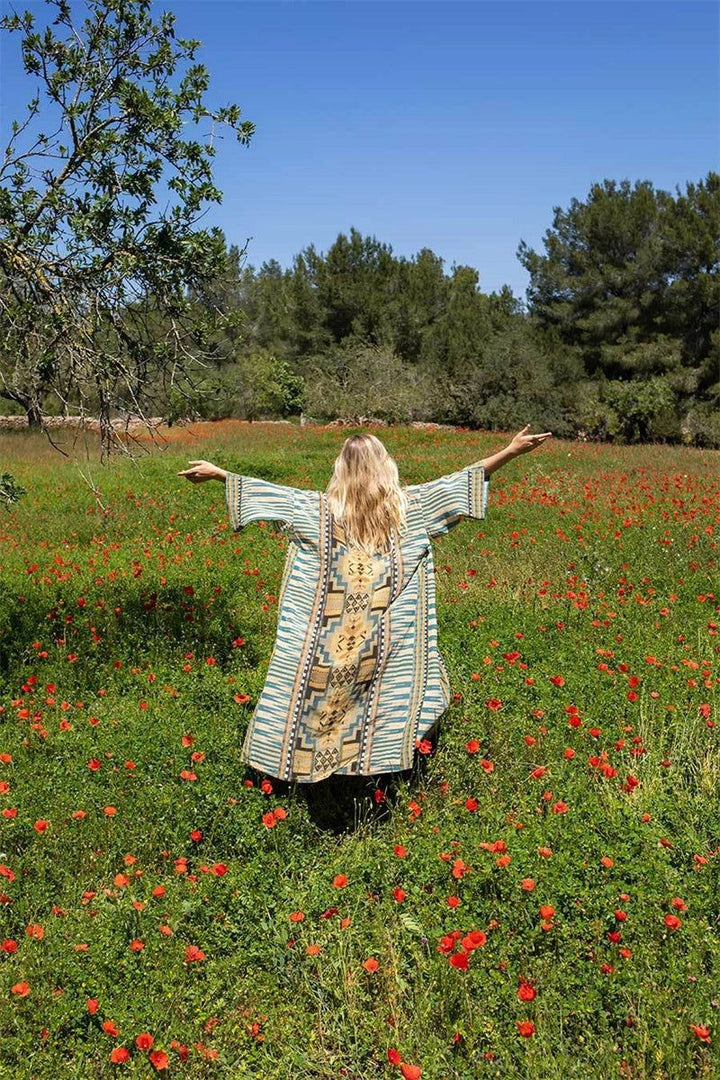 Femme portant un kimono fleuri dans un champ de coquelicots. Découvrez notre collection de kimonos uniques et colorés. Élégance et confort pour toutes les occasions.