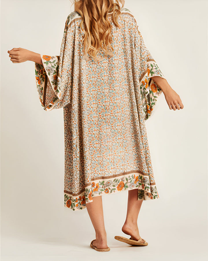 Vue arrière d'une femme portant un kimono long à motifs floraux. Kimono ample avec larges manches et bordures à fleurs. Mode kimono pour femme.