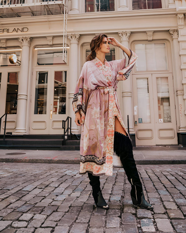 Femme portant un kimono fleuri rose dans la rue. Notre collection de kimonos pour femmes, élégante et confortable. Découvrez nos motifs uniques et variés.