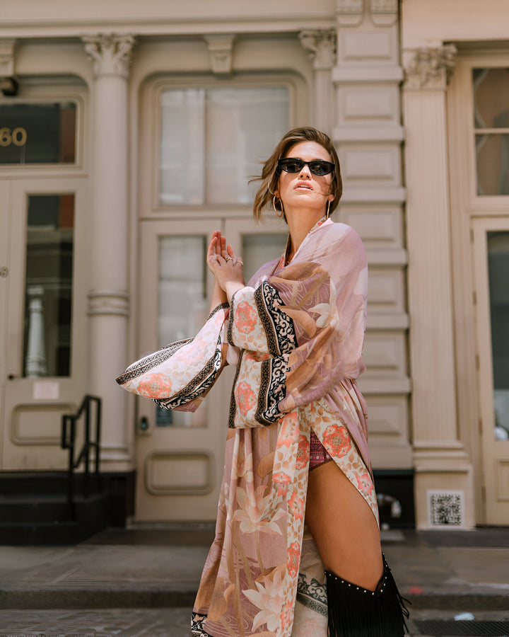 Femme portant un kimono fleuri rose et orange en extérieur. Kimono long, stylé et confortable. Mode kimono tendance.
