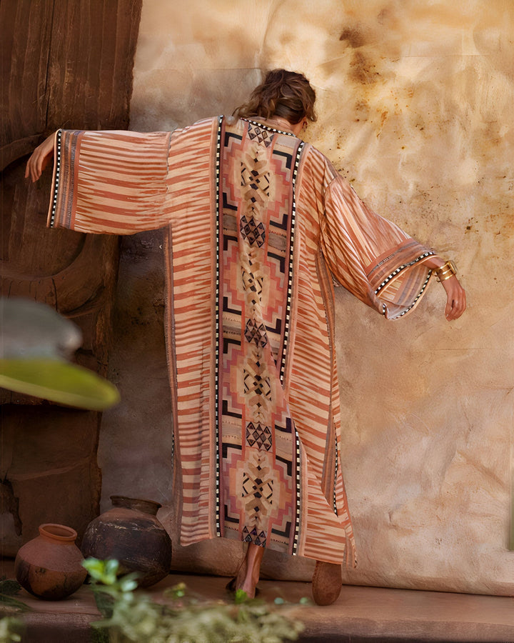 Femme portant un kimono long à motifs ethniques et rayures. Vêtement ample et confortable, idéal pour la maison ou la plage. Collection de kimonos uniques et originaux.