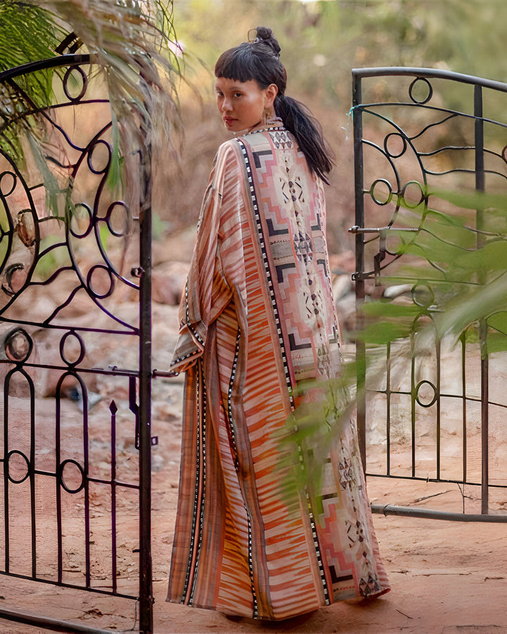 Femme portant un kimono long à motifs géométriques près d'une porte en fer forgé. Découvrez notre collection de kimonos élégants et originaux.