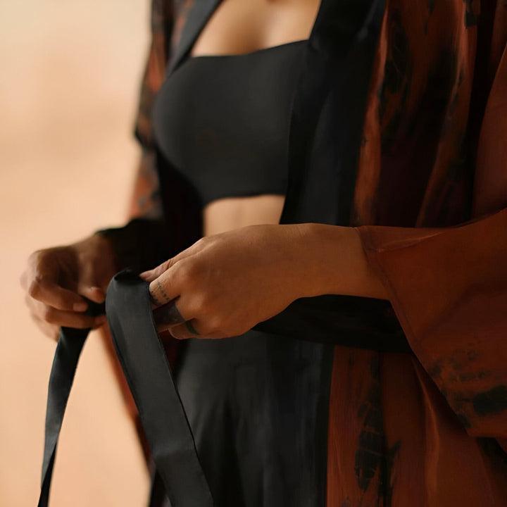Femme ajustant la ceinture d'un kimono imprimé. Vente de kimonos de qualité, différentes couleurs et motifs disponibles. Découvrez notre collection!