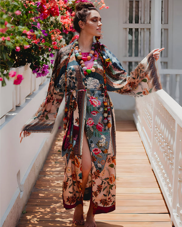 Femme portant un kimono fleuri coloré avec des manches amples et un collier de perles, posant sur un pont en bois. Collection de kimonos.