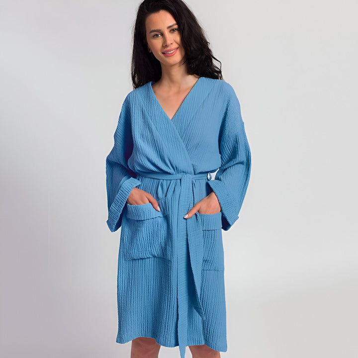 Femme souriante portant un kimono bleu clair. Peignoir kimono confortable avec ceinture et poches. Vêtements d'intérieur relaxants. Boutique de kimonos.