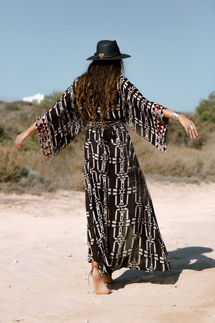 Kimono long à motifs noir et blanc, porté avec un chapeau et des bijoux argentés. Vue de dos, bohème chic, mode kimono.