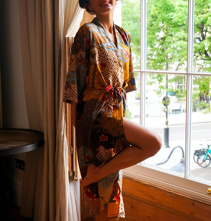 Femme souriante portant un kimono à motifs devant une fenêtre. Vêtements de détente élégants. Découvrez notre collection de kimonos uniques.