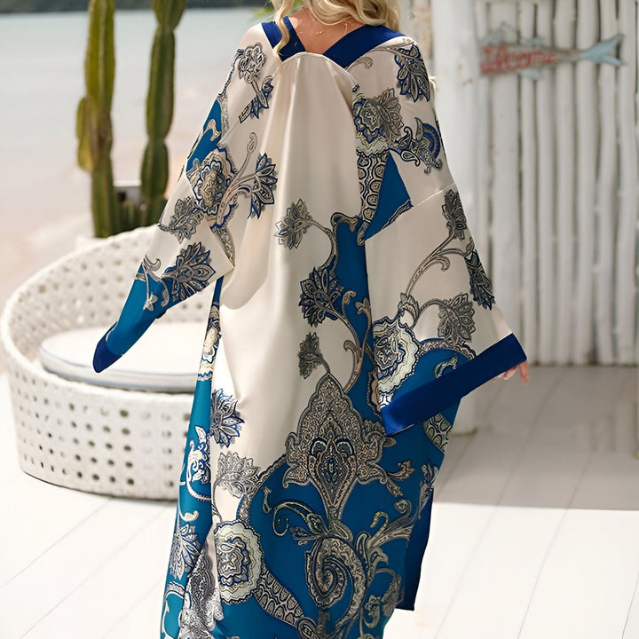 Femme portant un kimono bleu et blanc à motifs floraux. Kimono parfait pour la plage ou une tenue décontractée et élégante. Découvrez notre collection de kimonos uniques.