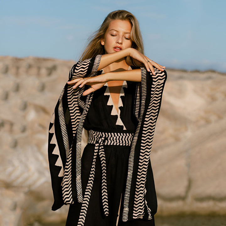Femme blonde portant un kimono noir et blanc à motifs. Style bohème et élégant, parfait pour la plage ou une soirée. Découvrez notre collection de kimonos uniques.