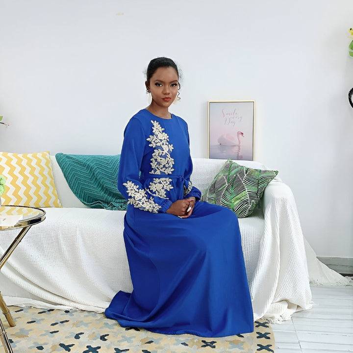 Femme assise portant une robe kimono bleue avec broderies florales dorées. Vente de kimonos élégants et confortables.