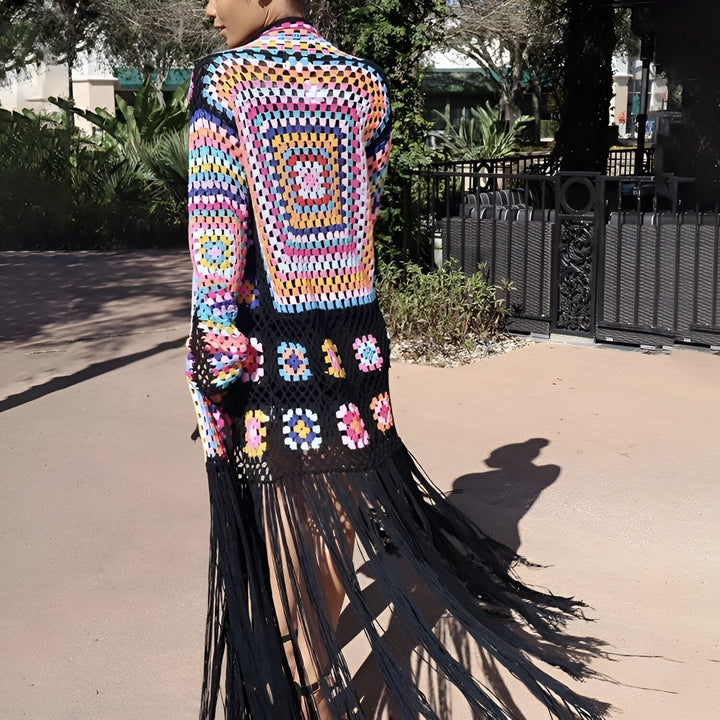 Femme portant un kimono long en crochet multicolore avec franges noires. Vêtement de mode style bohème. Kimonos uniques à découvrir dans notre boutique en ligne.