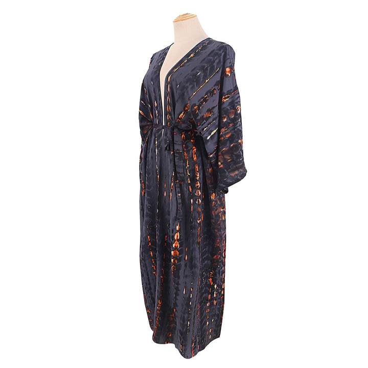 Kimono long à motifs tie-dye noirs et orange sur mannequin. Vêtement de détente élégant, idéal comme peignoir ou robe d'intérieur. Découvrez notre collection de kimonos uniques.
