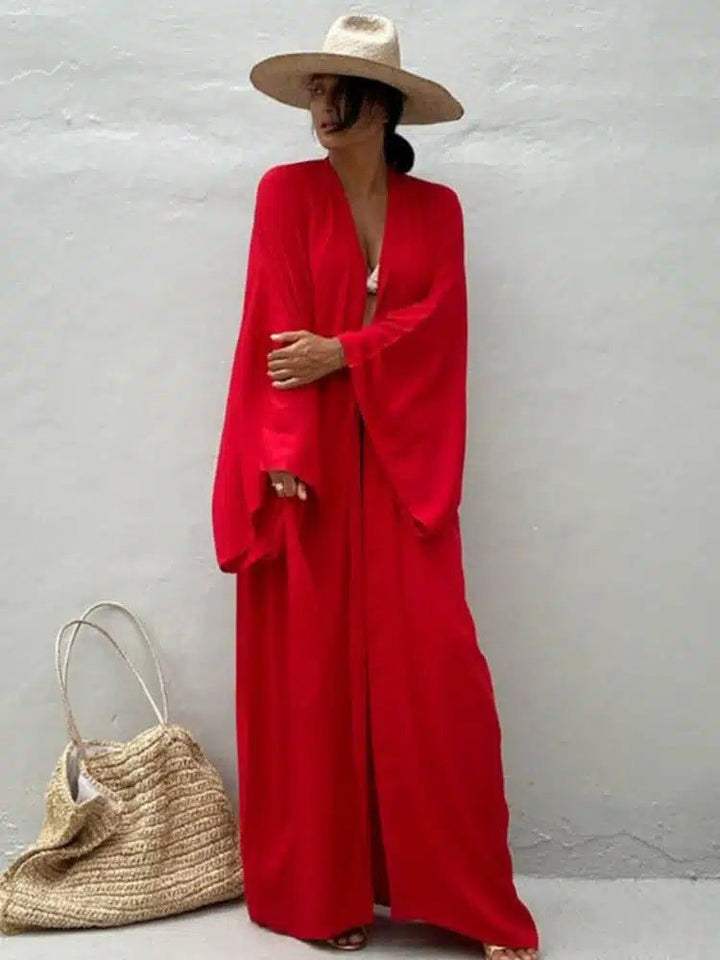 Femme portant un kimono rouge élégant et un chapeau de paille. Vêtements de plage chic. Découvrez notre collection de kimonos de haute qualité.