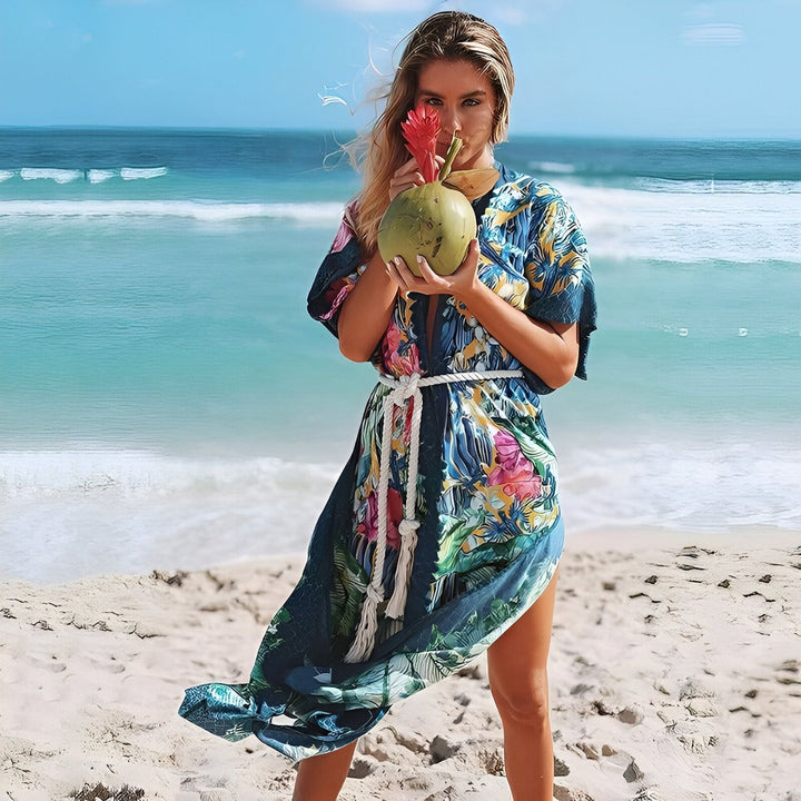 Femme sur la plage portant un kimono fleuri, tenant une noix de coco avec une fleur. Collection de kimonos pour femme, vêtements de plage tendance.