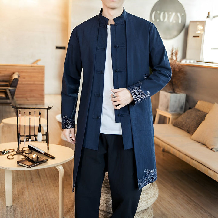 Homme portant un kimono bleu long avec des motifs traditionnels sur les manches et le bas. Vêtements de style japonais, vente de kimonos en ligne.