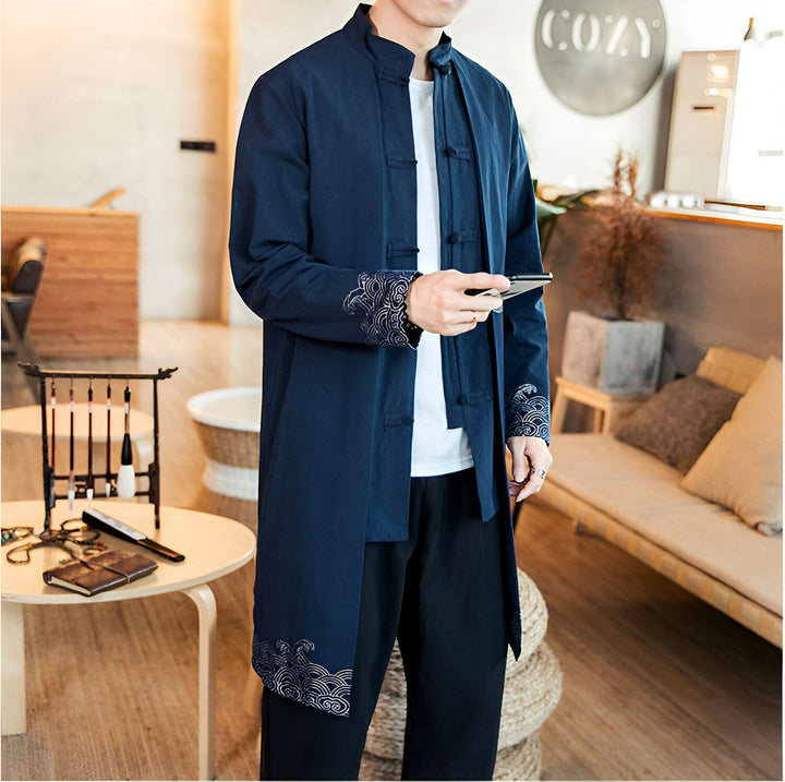 Homme portant un kimono bleu marine long avec des motifs brodés. Vêtements japonais traditionnels, mode masculine, vente de kimonos en ligne.